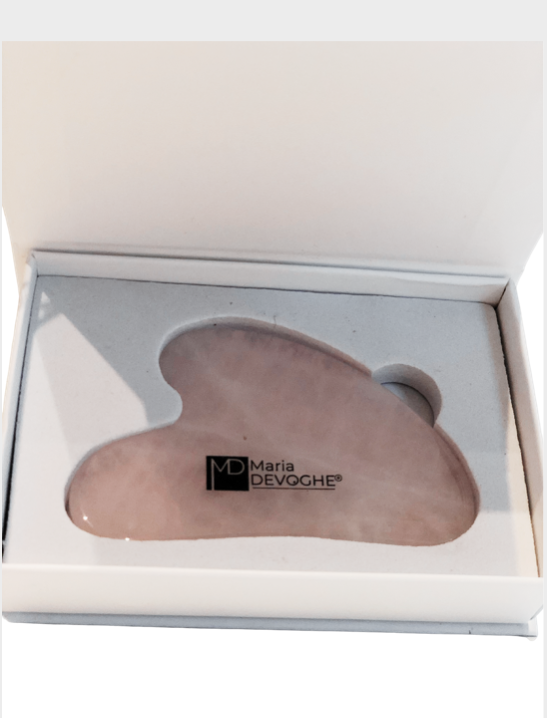 Gua Sha visage en quartz rose dans sa boîte, forme ondulée avec logo “Maria Devoghe” gravé dessus, utilisable pour lifting et fermeté.