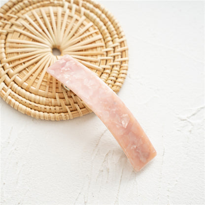 Barrette en pierre rose (9 cm) posée sur un dessous rond en osier.