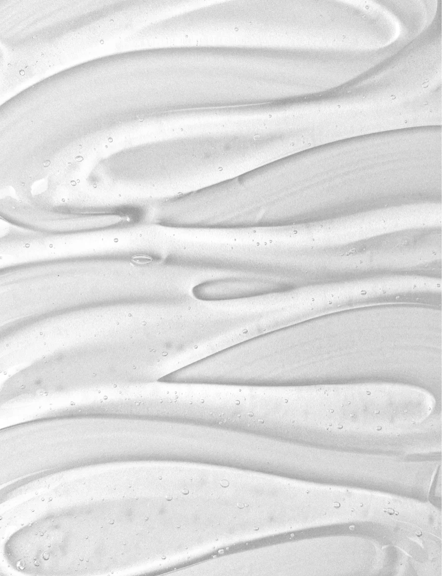 Texture de crème lisse et humide, couleur gris clair, évoquant une pâte onctueuse pour soins de la peau sensibles.