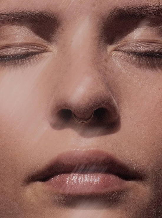 Visage de femme en gros plan avec teint lumineux, yeux fermés, lèvres légèrement humectées. Sérum huileux naturel au Bakuchiol évoqué par l’éclat et la douceur de la peau.