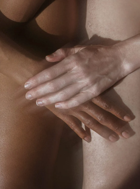 Crème pour le corps 5% Urée + 2% Panthenol: deux mains se caressant mutuellement, peau claire et peau foncée en arrière-plan.