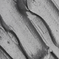 Texture argentée d’un masque à l’argile lissé en vagues curvilignes, détails granuleux et zones brillantes. Masque pour pores dilatés et points noirs.
