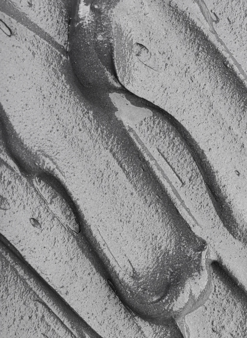 Texture argentée d’un masque à l’argile lissé en vagues curvilignes, détails granuleux et zones brillantes. Masque pour pores dilatés et points noirs.