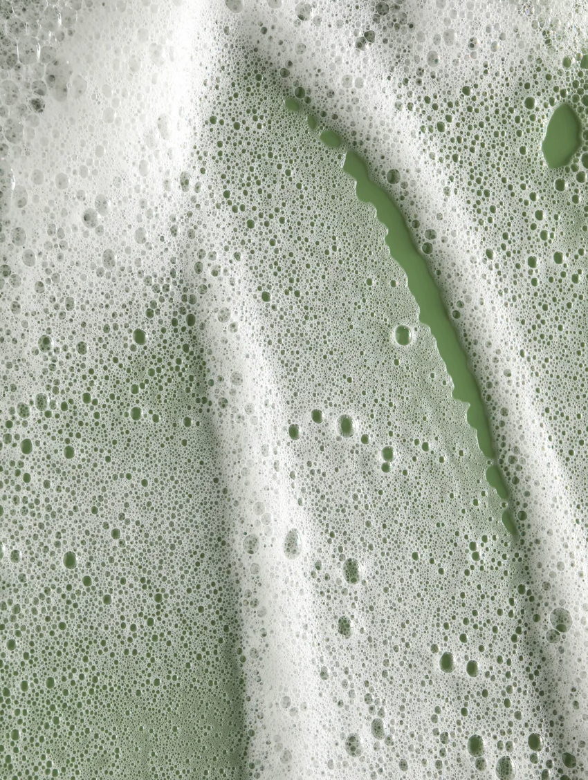 Mousse fouettée verte et blanche, texture épaisse et effervescente, idéale pour un nettoyant visage purifiant anti-acné.
