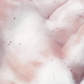 Pâtes mousseuses roses sur peau lavée, aspect clair et aérien, démontrant le nettoyant visage purifiant anti-acné en action.